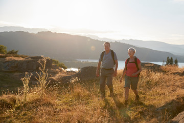 Fototapeta premium Senior Couple Walking On Top Of Hill On Hike Through Countryside In Lake District UK