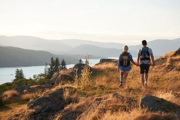 Rear View Of Couple Walking On Top Of Hill On Hike Through Countryside In Lake District UK