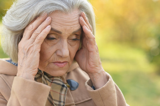 Portrait Of Sad Senior Woman With Headache Posing Outdoors