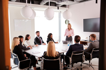 Mature Businesswoman Addressing Group Meeting Around Table At Graduate Recruitment Assessment Day
