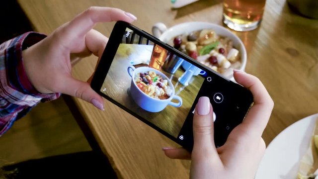 Rice gruel and cheese cakes. Female hands taking photo of breakfast food by smartphone. 4K