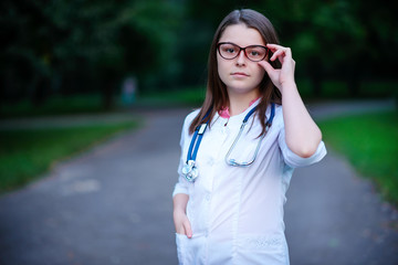 Serious look. a young girl who is a doctor stands outside,holds