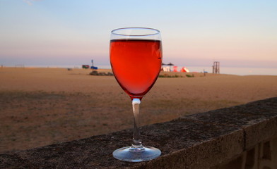 a glass of red wine on the background of the beach 
