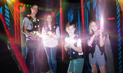 Obraz na płótnie Canvas Brother and sister playing laser tag in beams