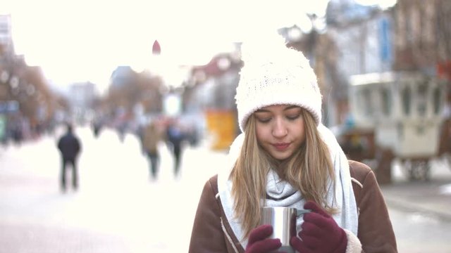 Girl on the street.
Girl stands on the Arbat, wind blows in the face. She drinks hot drink. Perspective of the main street of the city. Arbat is filled with people. Rush hour.