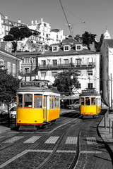 Fototapeta na wymiar Yellow tram on old streets of Lisbon, Alfama, Portugal, popular touristic attraction and destination. Black and white picture with a coloured tram.