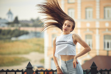 Fototapeta premium portrait of a girl in jeans and a t-shirt on the background of the building in the evening on a summer day. street dancing in the city