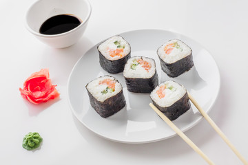 Roll of sushi on a plate, Sushi roll on a tablet on the table restaurant / eating sushi roll using chopsticks, white background, Sushi roll and hand with chopsticks. Japanese food.
