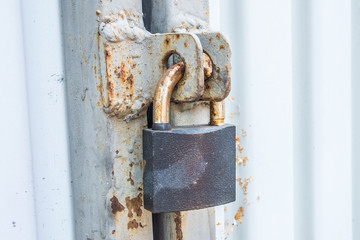 Closeup of old rusty lock on gray metal garage door.