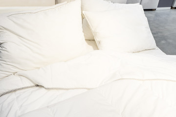 white pillow on bed and with wrinkle messy blanket in bedroom, from sleeping in a long night, an unmade bed in hotel bedroom with white blanket.