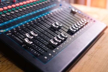 The DJ is adjusting the volume of the sound. Professional audio mixing console