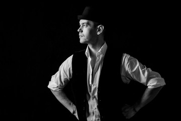 Portrait of an old-fashioned man in a white shirt with suspenders and a cylindrical hat. Isolated on dark background