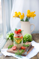 Salad in the bank on the table by the window. Delicious healthy food from spring vegetables.