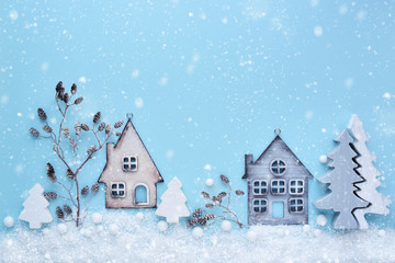 Christmas composition with toy houses, twigs and trees with snow on a blue background. New Year background. Beautiful greeting card. Top view