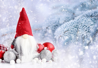 Christmas gnome with festive decorations on a background snow-covered fir branches. Christmas or...