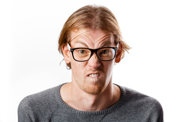 Male portrait of a fair-haired man of European appearance, on a white background. Emotions. Nerd hipster in eyeglasses sitting on a chair. Young worried nerd man. Stupid face. Botanist. Man in glasses