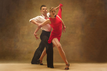Flexible young modern couple dancing tango in studio. Fashion portrait of attractive dancing couple. Man and woman. Passion. Love. perfect skin facial and make-up. Human emotions - love and passion
