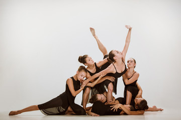 The group of modern ballet dancers dancing on gray studio background