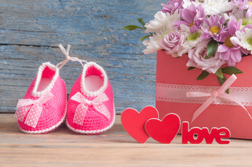 Small child shoes and beautiful flower bouquet on the wooden table