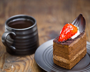 Chocolate cake in saucer next to mug of coffee on distressed wood