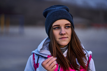 Portrait of a young beautiful girl with dark brown hair in a sports hat and jacket in the first...