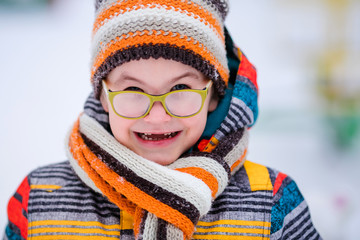 Smiling boy with green big glasses, knitting hat and scarf. Winter snowy background