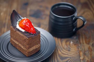 Chocolate cake in saucer next to mug of coffee on distressed wood