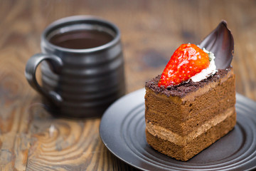 Chocolate cake in saucer next to mug of coffee on distressed wood