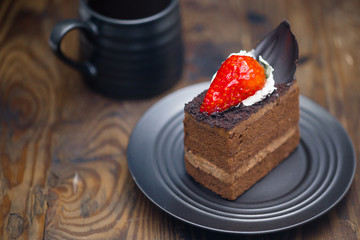 Chocolate cake in saucer next to mug of coffee on distressed wood