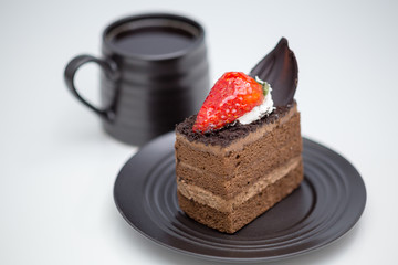 Slice of chocolate cake in saucer next to mug of coffee