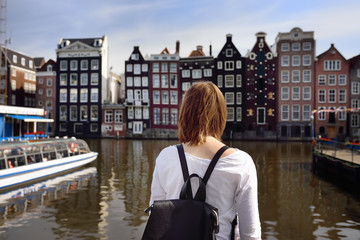 Fototapeta na wymiar Young woman looking at the famous dancing houses of Amsterdam on sunny day