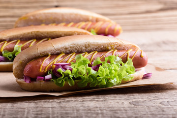 Hot dog with yellow mustard, lettuce and onions