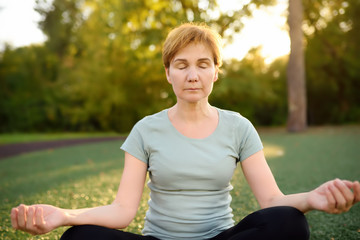 Mature woman practicing yoga outdoor exercise or meditating
