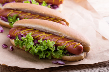 Hot dog with yellow mustard, lettuce and onions