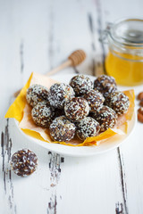 healthy energy organic bites with nuts, dates, honey and sesame in a plate on a light wooden background.