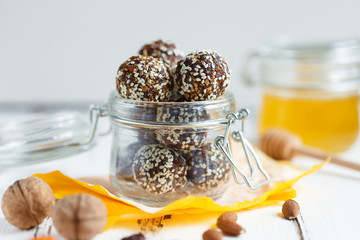 Obraz na płótnie Canvas healthy energy granola bites with nuts, dates, honey and sesame in a glass jar on a white table