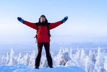 traveler man with backpack in winter landscape waving his hand in greeting and smiling