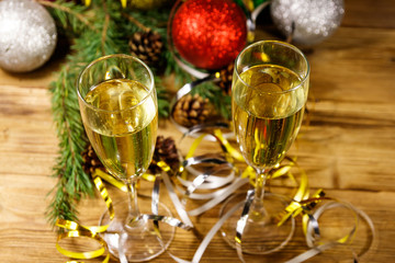 Two glasses of champagne and festive Christmas decorations on wooden table. Christmas and New Year celebration