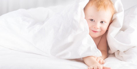 Habby young smilling child boy in white bed