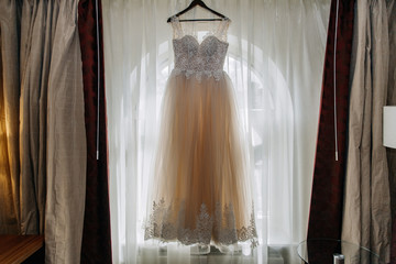 Wedding dress hanging on a hanger on the window
