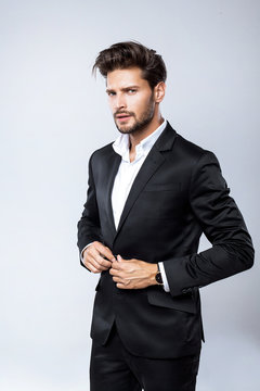 Sexy businessman in black suit buttoning up his jacket 