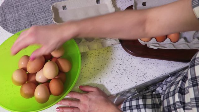 Woman selects whole hen eggs in a green bowl
