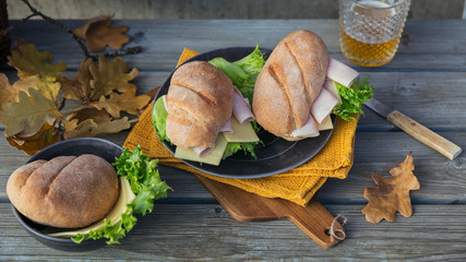 Ciabatta baguette sandwiches with ham, cheese, lettuce and a glass of beer