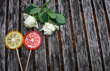 top view of white rose and Candy fruit on wooden background