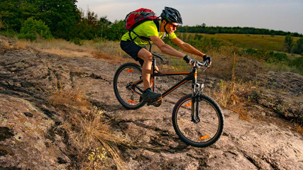 Cyclist Riding the Bike on Rocky Trail at Sunset. Extreme Sport and Enduro Biking Concept.