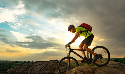 Cyclist Riding the Bike on Rocky Trail at Sunset. Extreme Sport and Enduro Biking Concept.