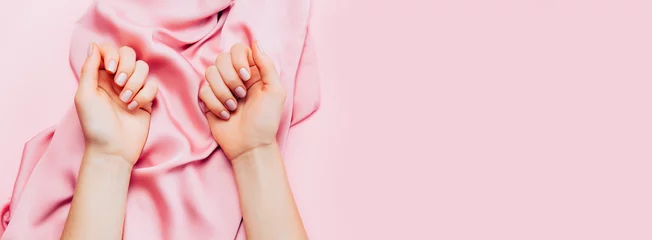 Fototapeten Schöne Frauenmaniküre auf kreativem trendigem rosa Hintergrund mit Seidenstoff. Minimalistischer Maniküre-Trend. Ansicht von oben, flach liegend. Kopieren Sie Platz für Ihren Text. © paninastock