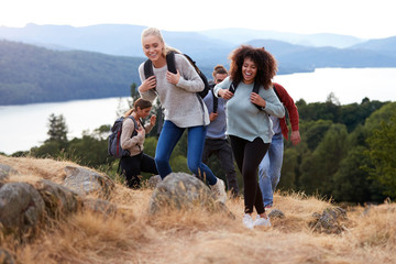 A group of five young adult friends smiling while hiking together to a mountain summit