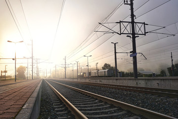 Fototapeta na wymiar Railway station in the morning on sunrise. Industrial landscape with railroad,Beautiful sky with mist, sunlight, trains in background. Railway junction. Heavy industry.Scenery in autumn winter.