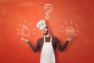 A young bearded chief makes a scale shape with his arms with an apple and a burger on each side from him.